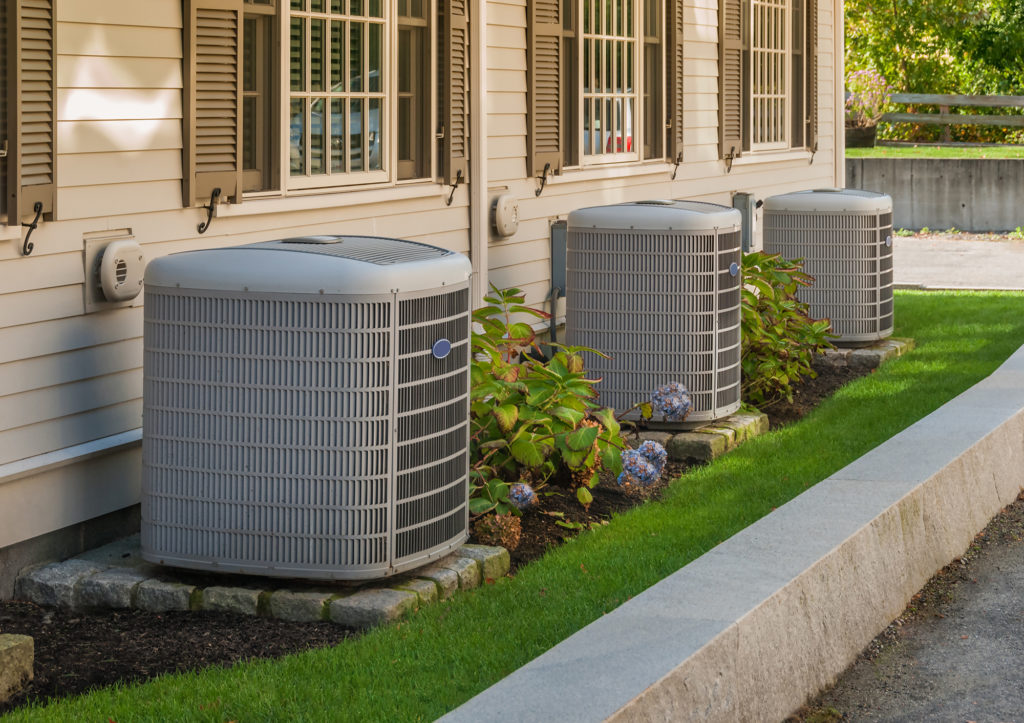 Residential air conditioning units installed along a home exterior